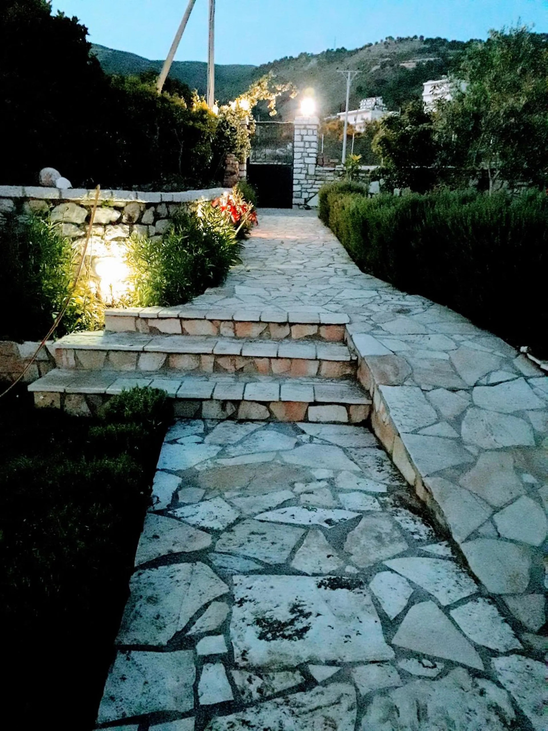 Stone steps and a flagstone path lit by small lamps at dusk