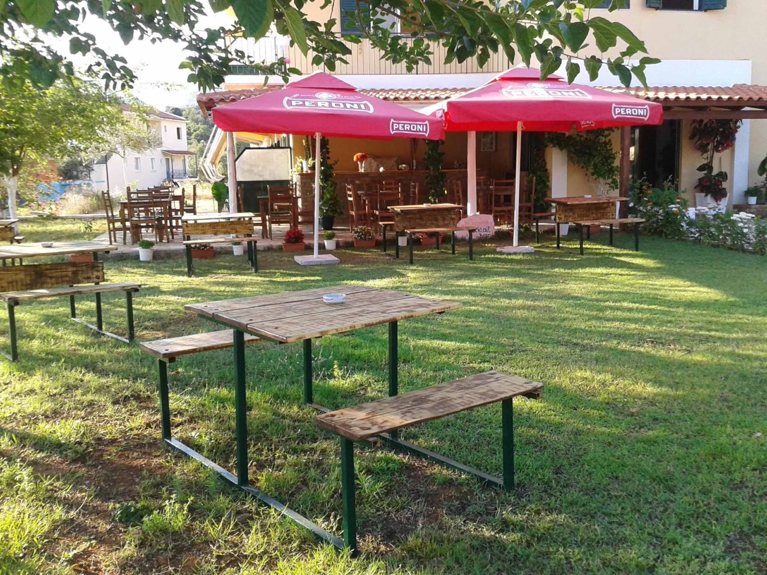 Wooden picnic tables on the lawn in front of the house and its pergola