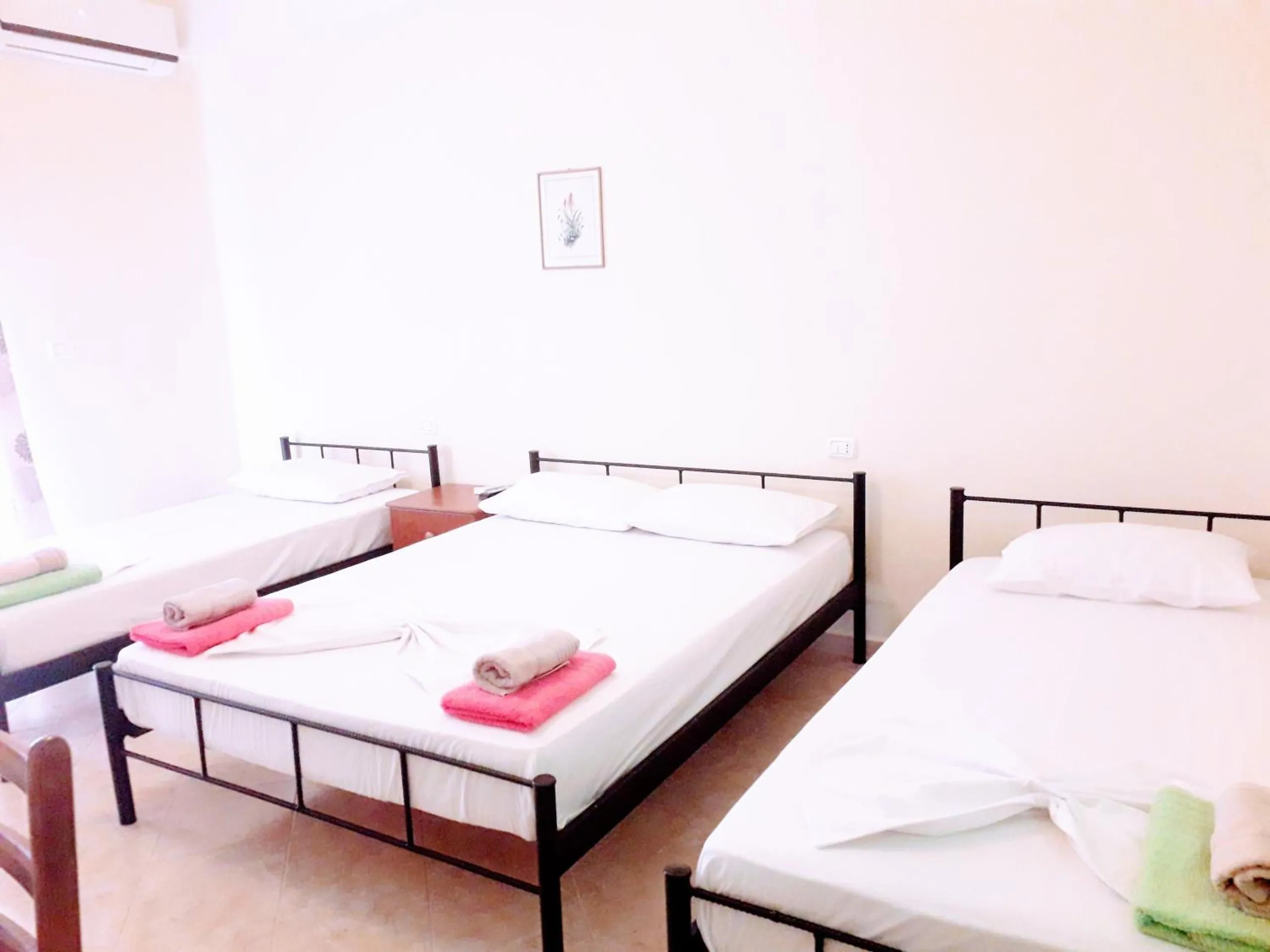 Three made-up beds with folded towels in a bright cream room