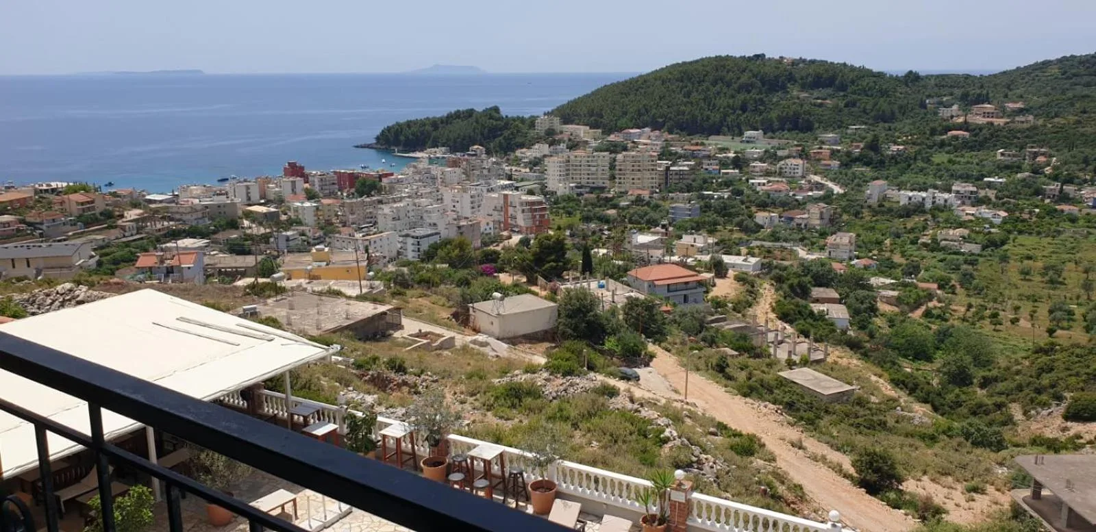 The view from a balcony railing over Himarë to the sea and the wooded headland