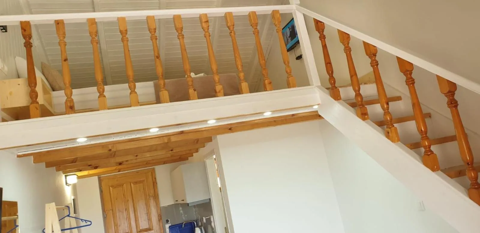 The duplex studio from below: a pine stair with turned balusters rising to the sleeping loft