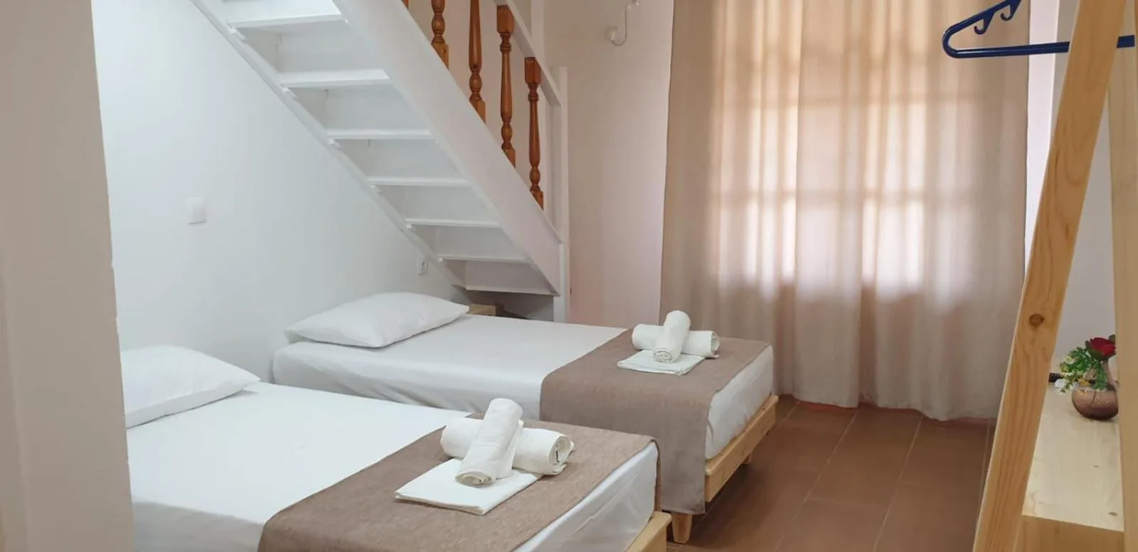 Two single beds made up with towels beside a white stair