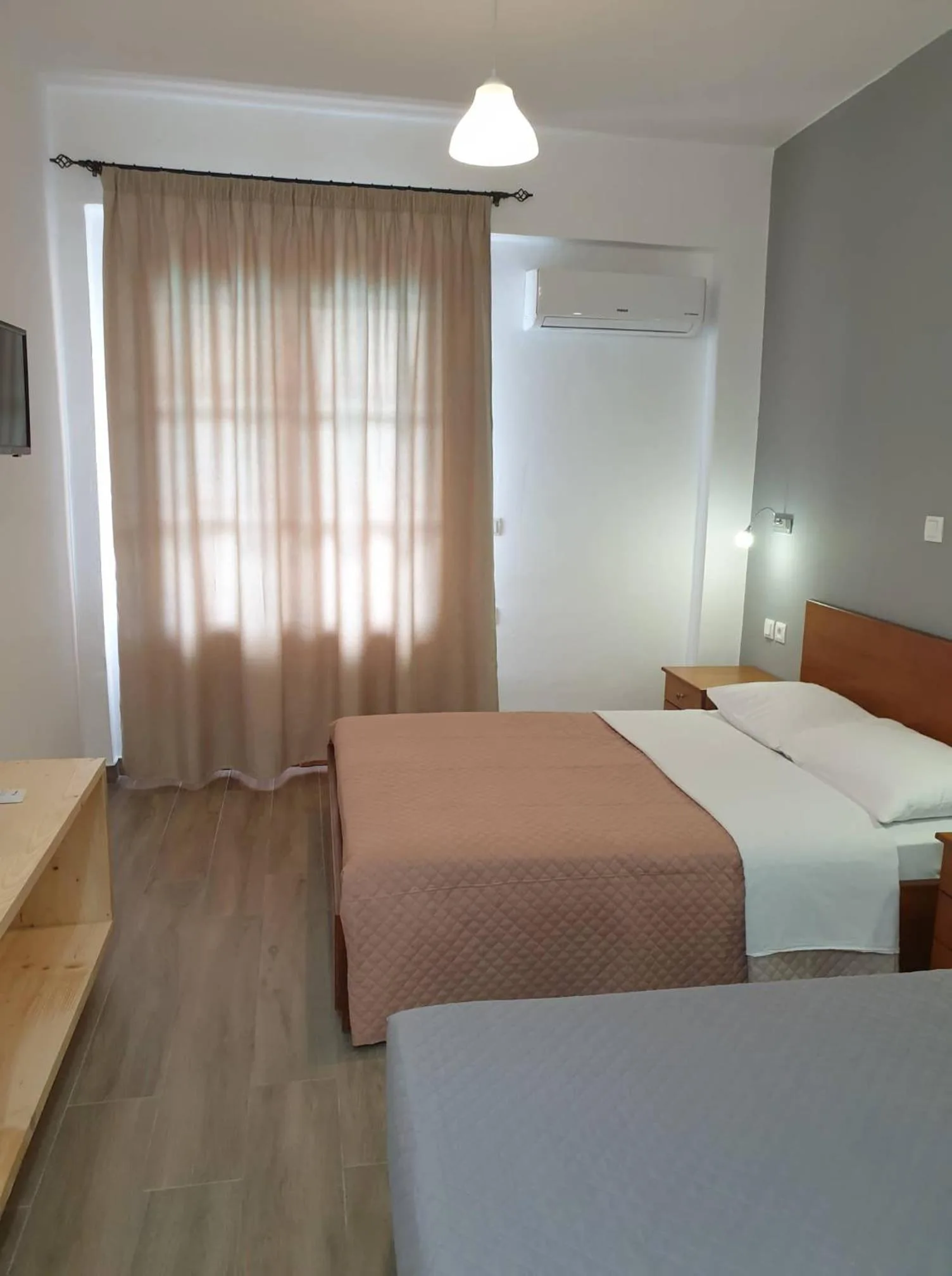 A studio with a double bed and a single bed, rose curtains at the balcony door