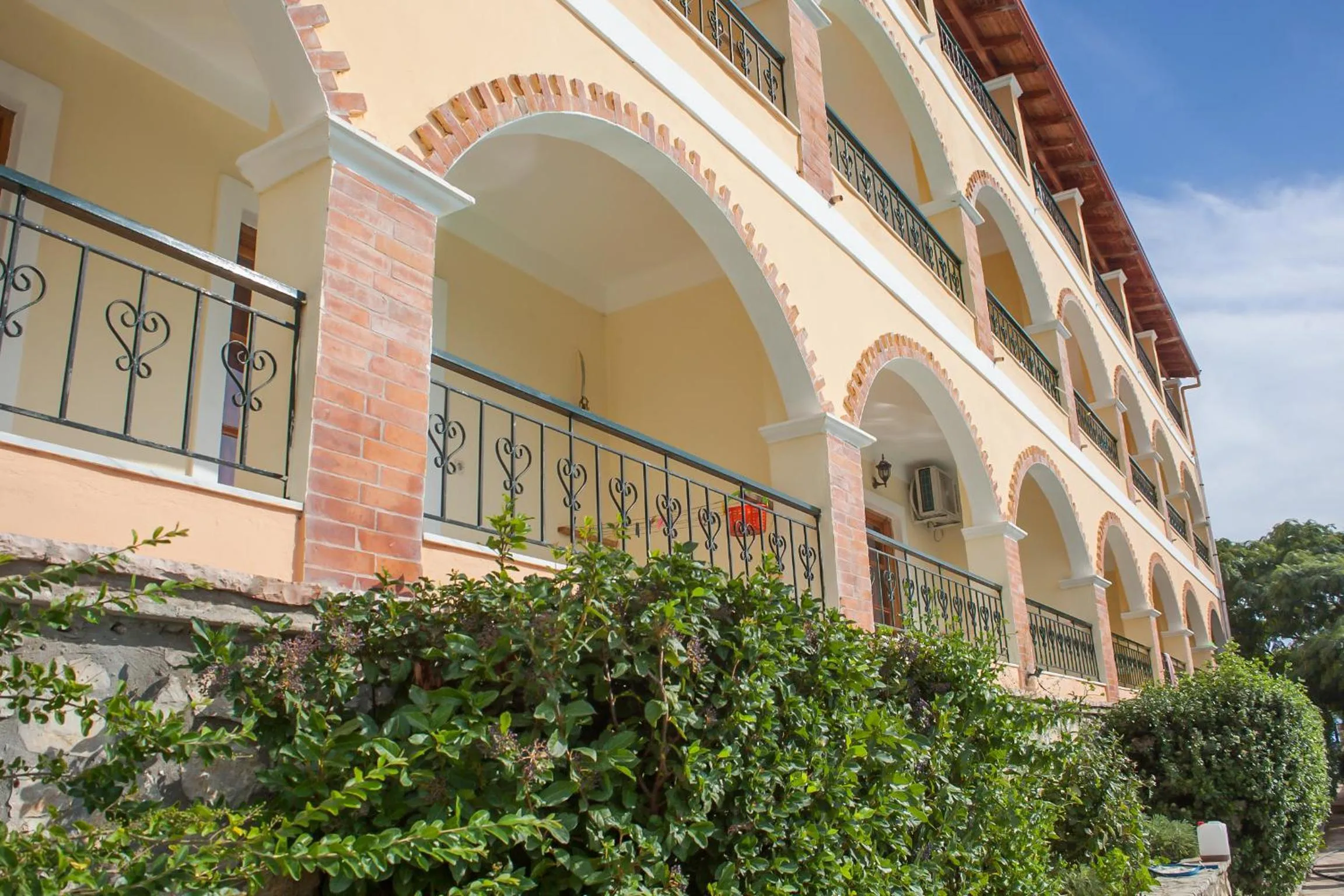 Close view of the arcades: cream render, brick-trimmed arches and wrought-iron railings