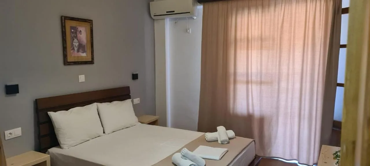 A bedroom with a double bed, a framed picture and long peach curtains
