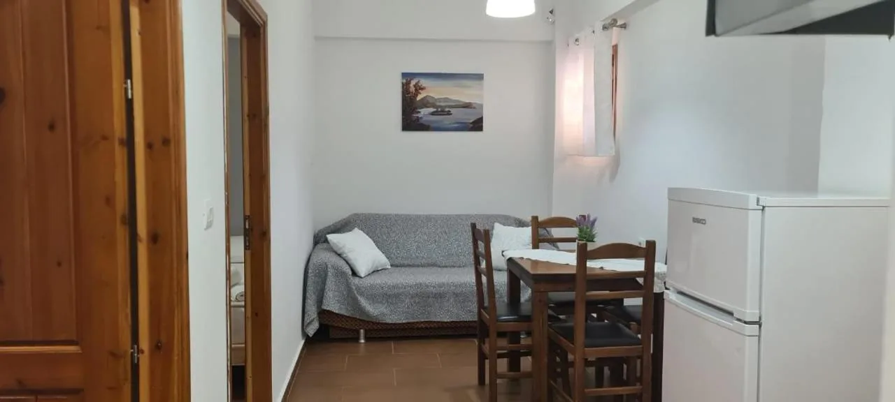 The living room: a grey sofa, a dining table and chairs and a fridge, pine doors either side