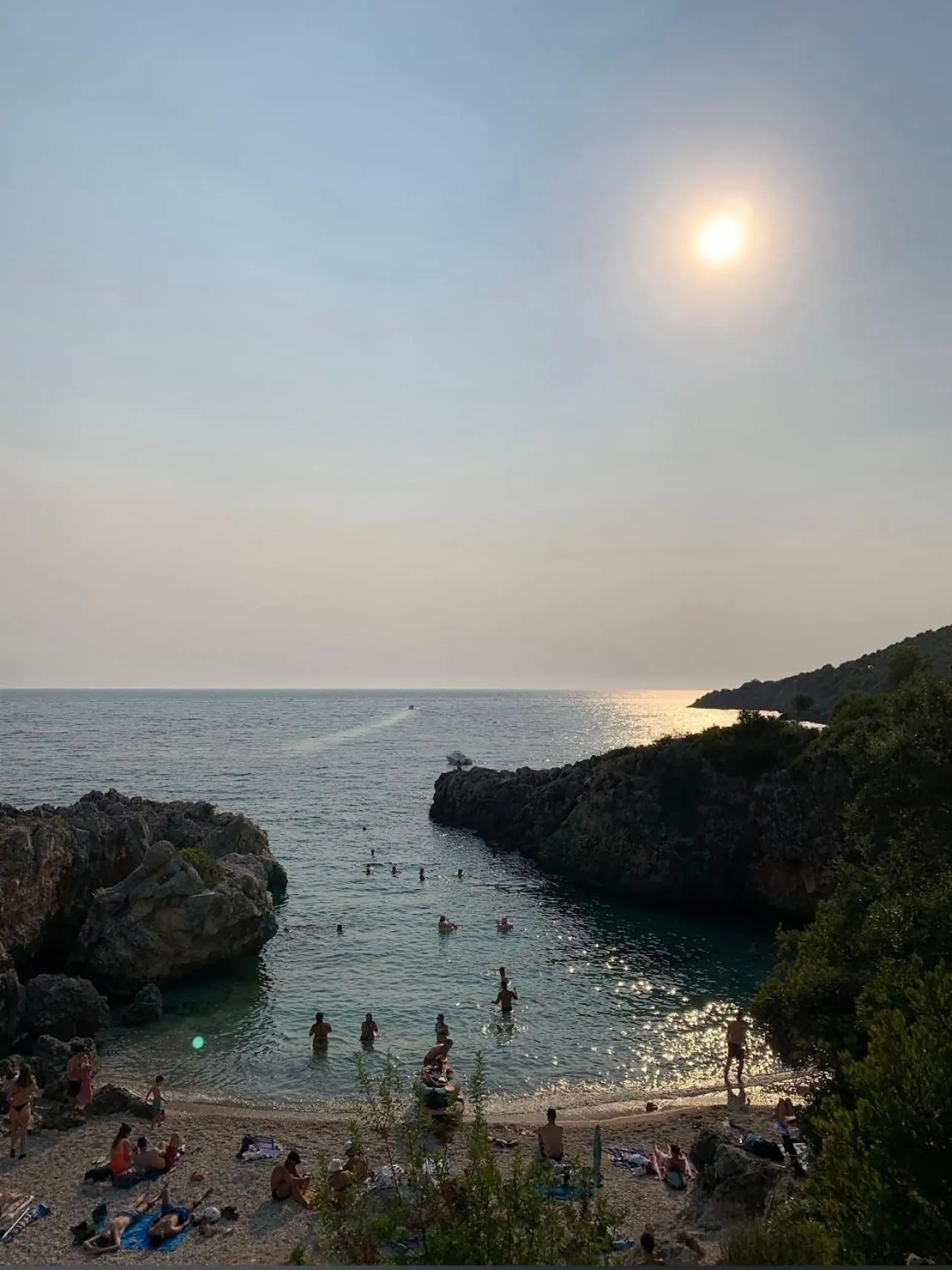 The afternoon sun over the mouth of the cove, swimmers in the shallows