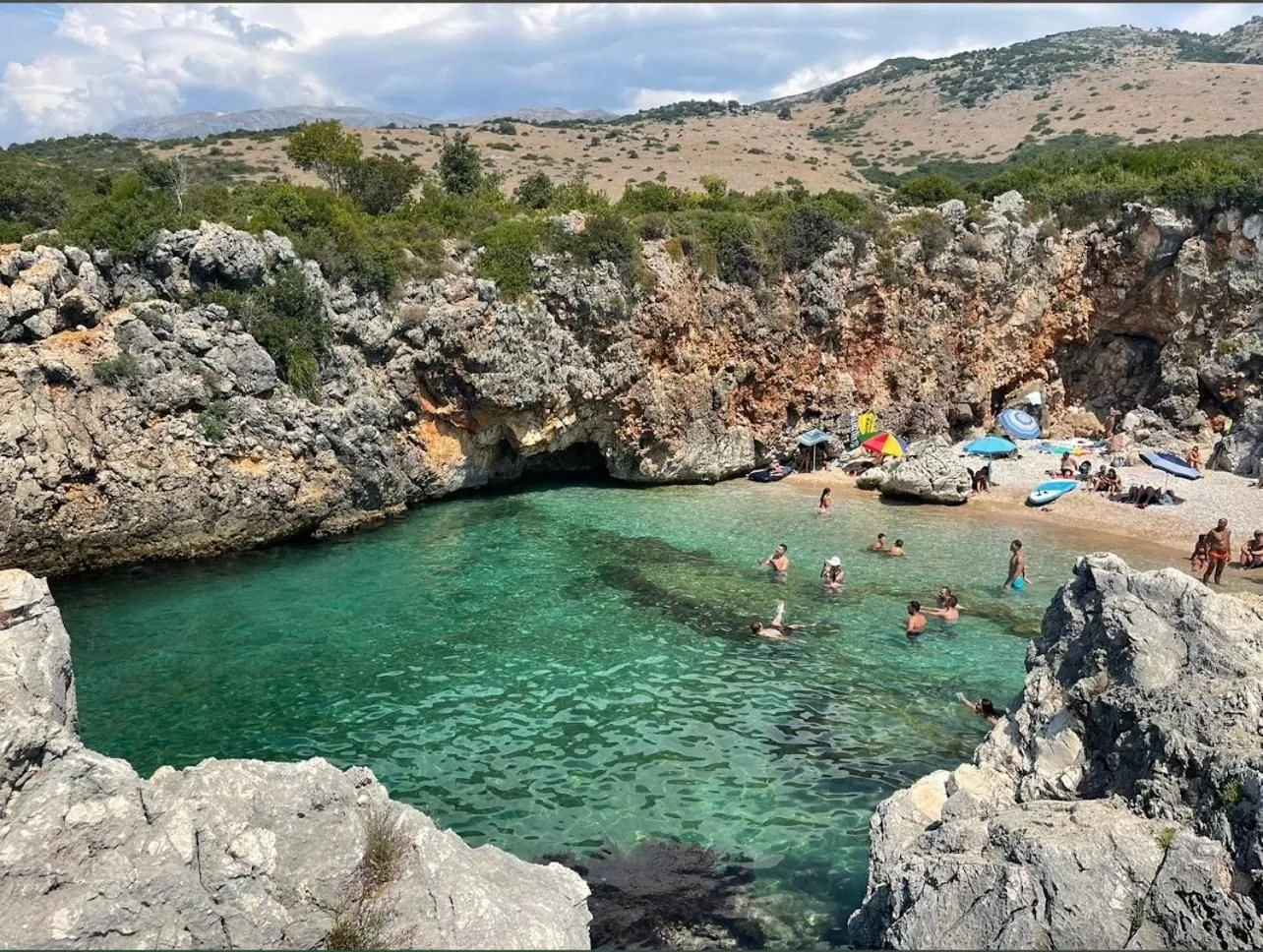 The cove seen from the rocks, its beach tucked under a pale limestone cliff