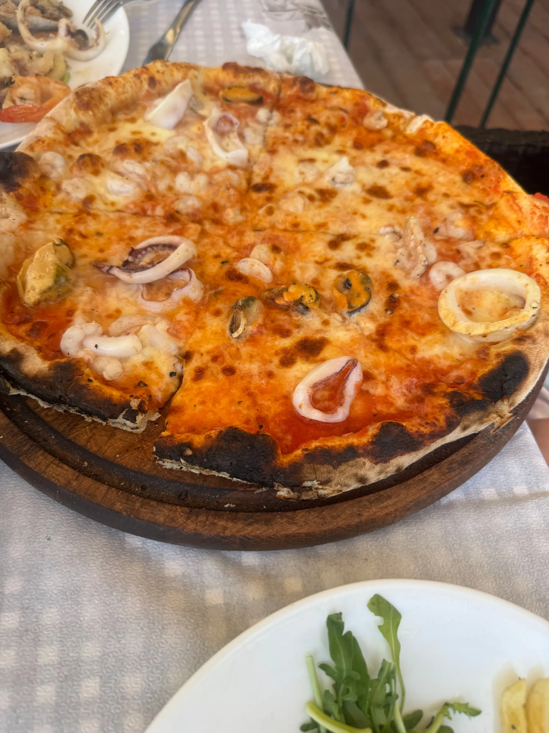 A seafood pizza with squid rings on a wooden board