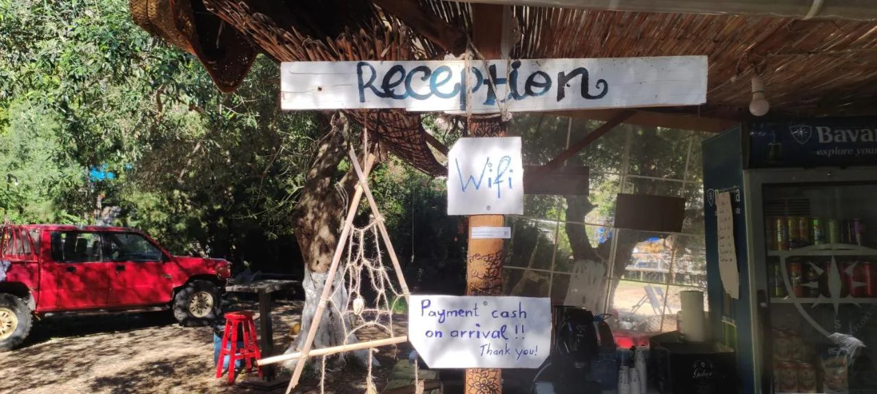 A hand-painted Reception sign on a white plank over the bar, with handwritten notes beneath it reading Wifi and Payment cash on arrival