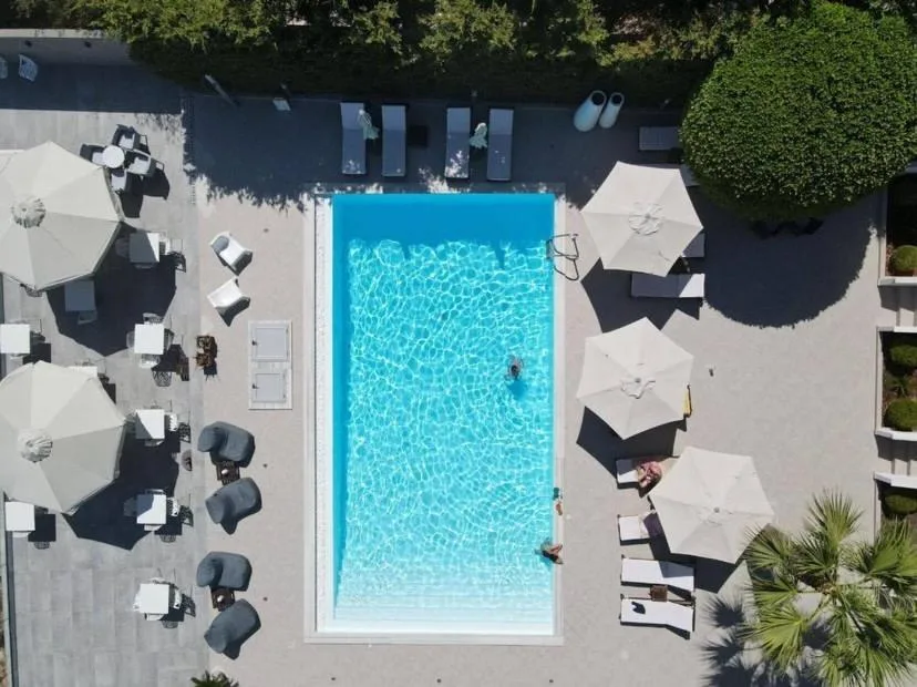 The pool photographed straight down from above, umbrellas and loungers along both sides