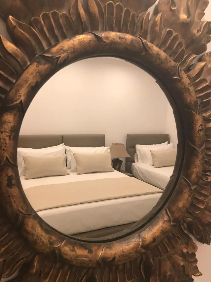 A gilt sunburst mirror reflecting a made-up double bed