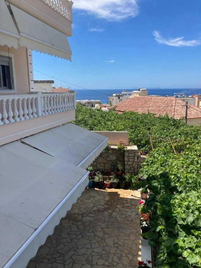 A white awning over the paved courtyard, with the vine below and the sea beyond the roofs