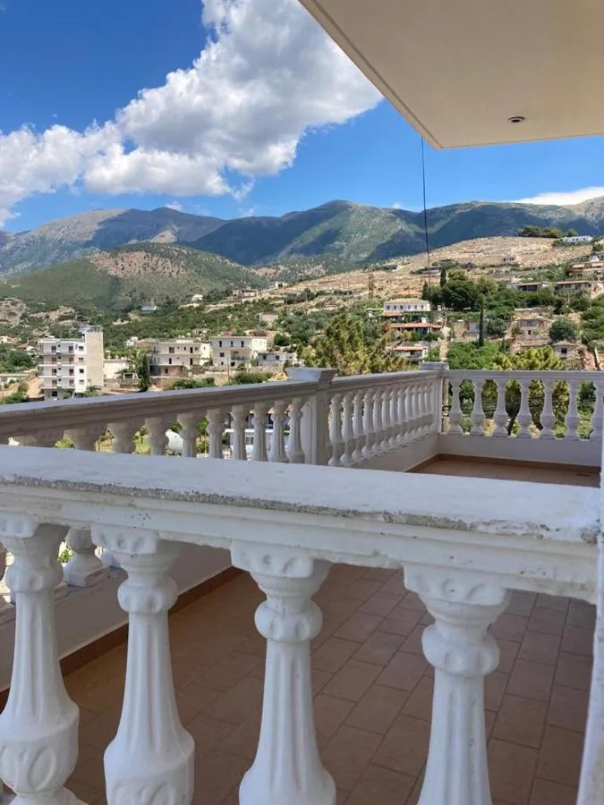 A white balustrade with the hills and mountains behind Himarë under a blue sky