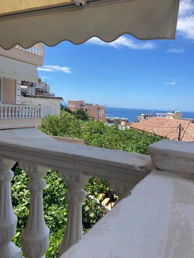 A balustrade corner with trees below and a strip of sea between the buildings