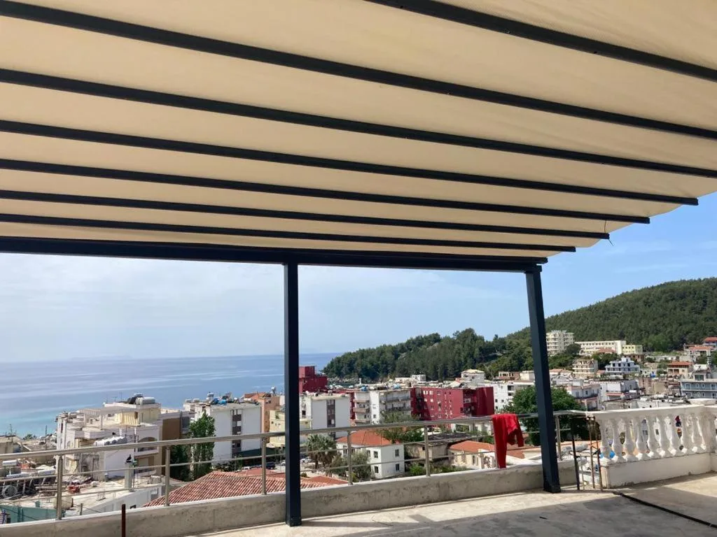 A covered terrace with a slatted roof looking over the town to the bay and the wooded headland