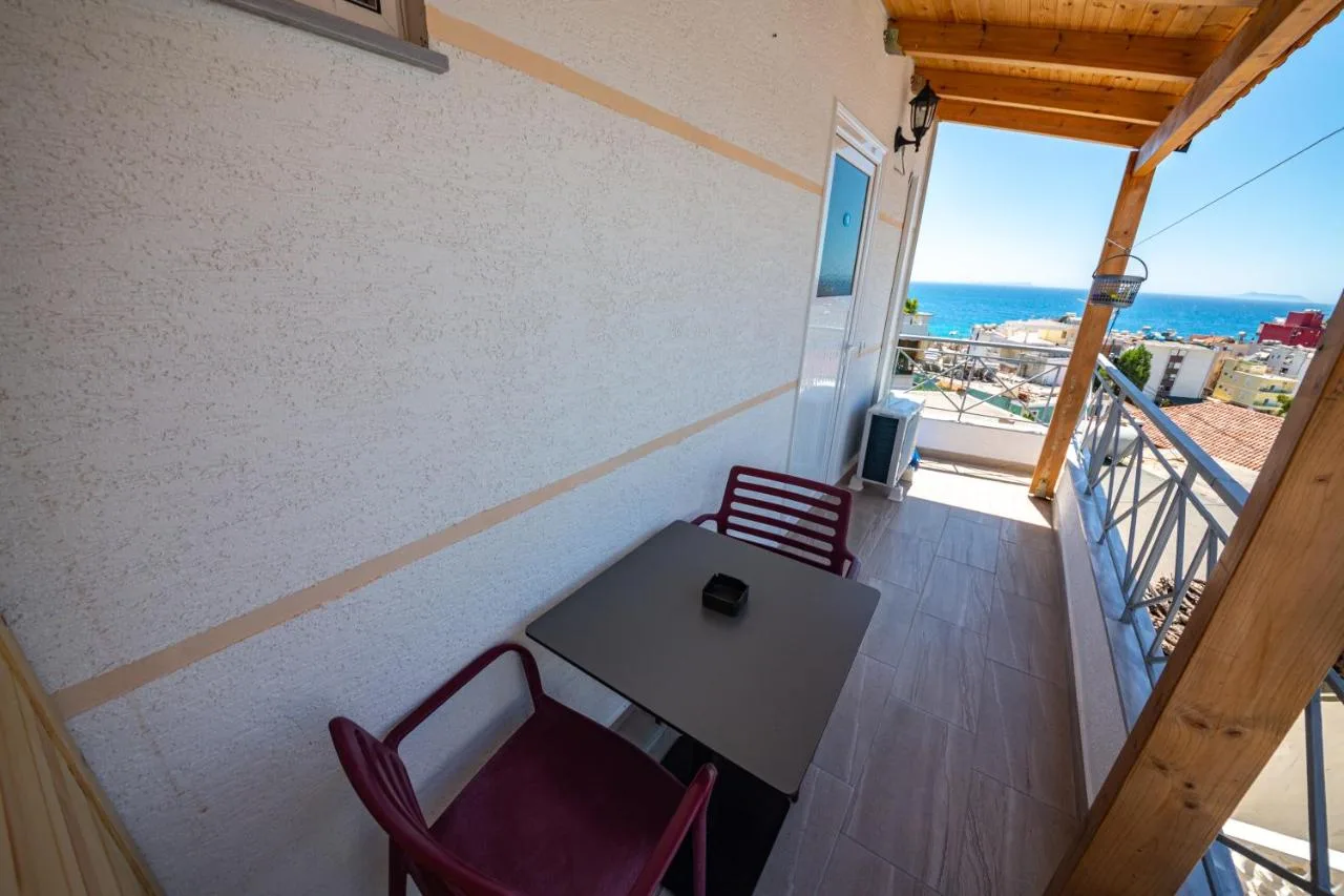 The covered balcony of the double studio, with a table, two chairs and the sea beyond the roofs