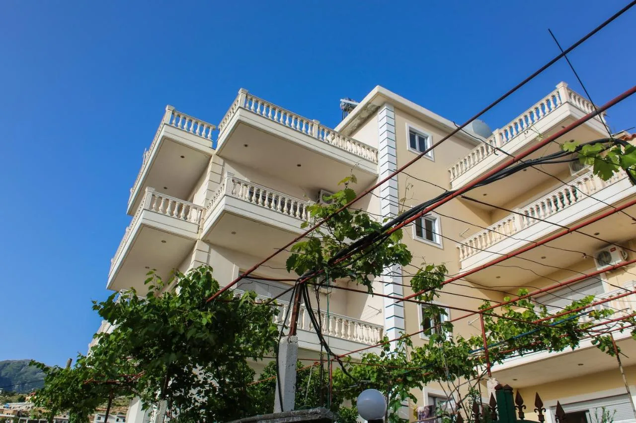 Himara Apartments seen from the lane below: four storeys of sand-coloured render with white balustraded balconies and a vine in front