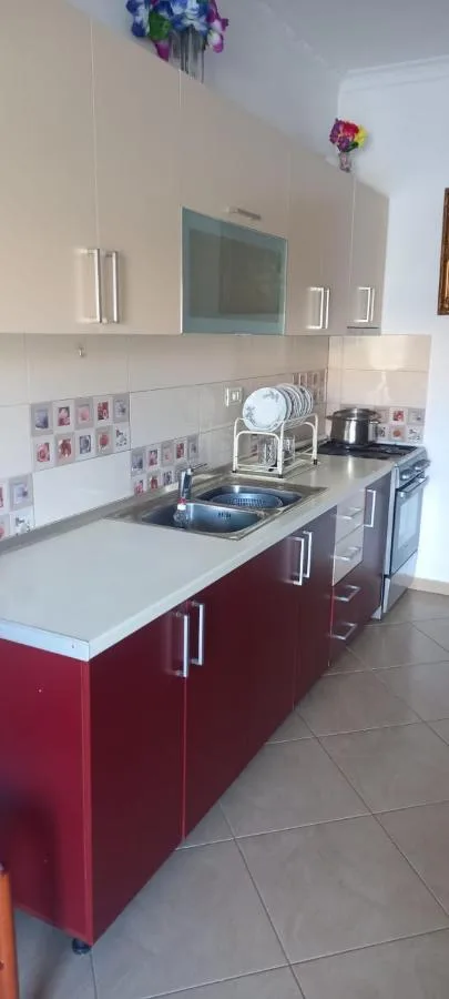 The ground-floor kitchen with red cabinets, a sink, a hob and a dish rack