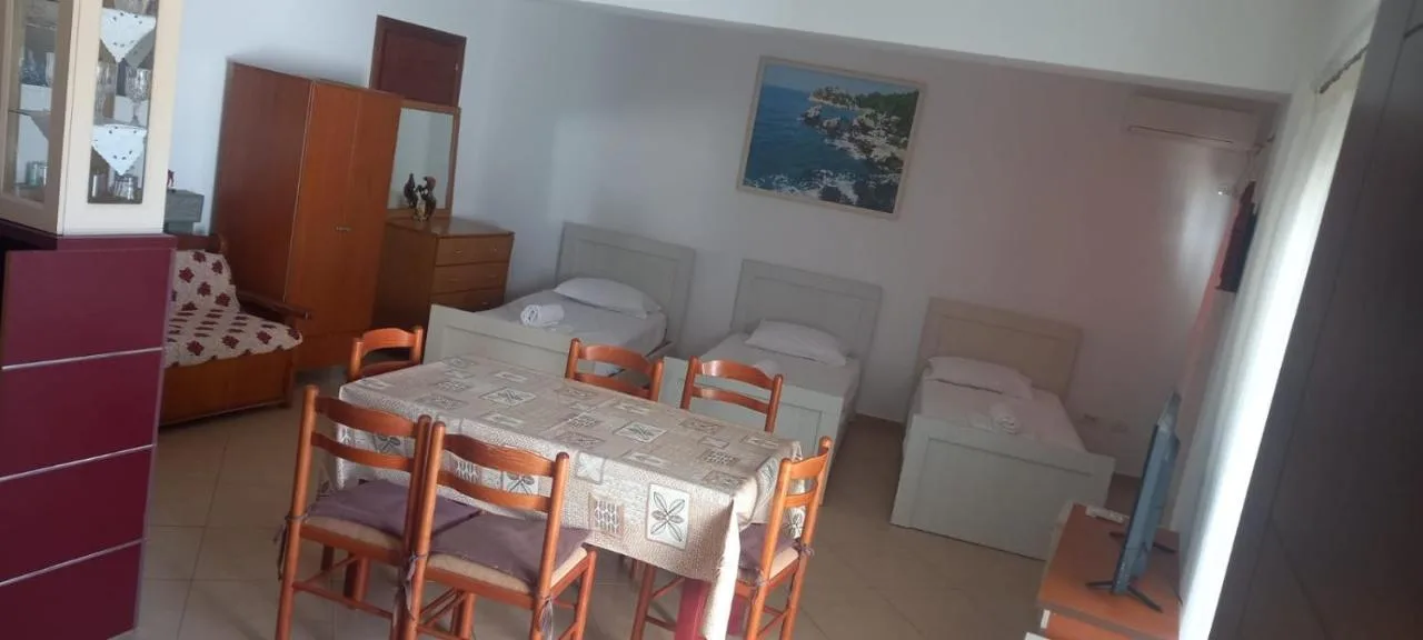 The living room of the ground-floor apartment: a long dining table with chairs, beds along the wall and a sea painting