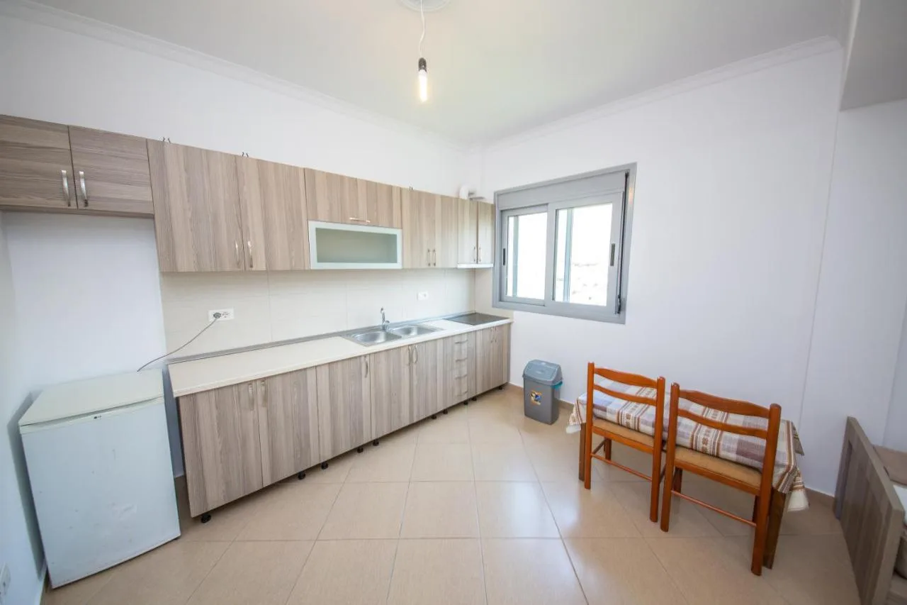 The kitchen of the one-bedroom apartment with a long counter, a small refrigerator and two chairs