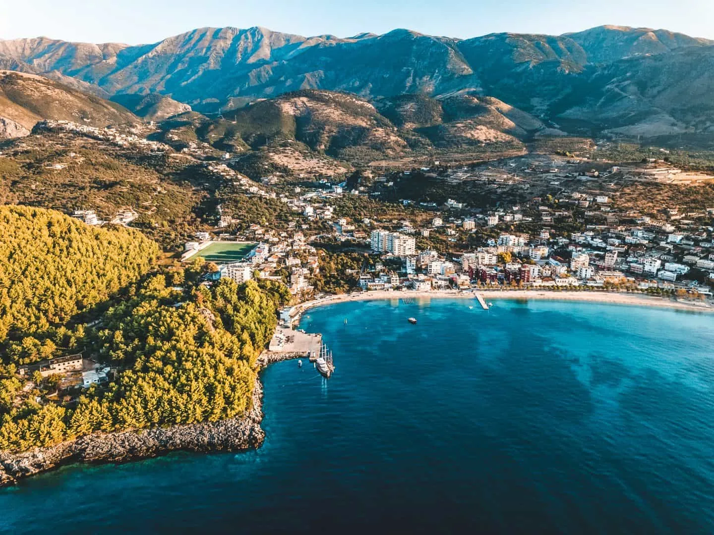 Spile bay at Himarë from the air: the long beach, the town behind it and the wooded headland