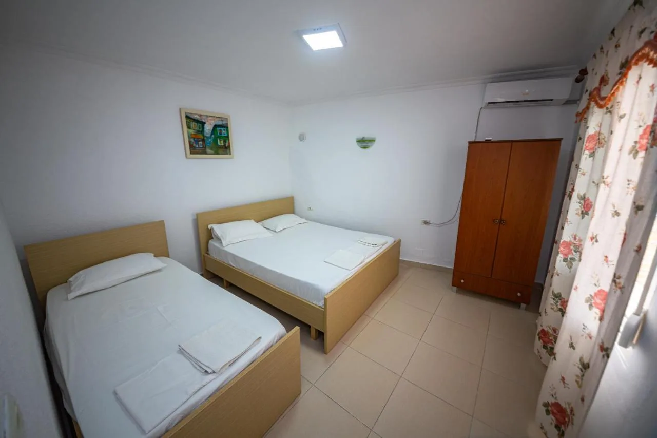 A studio with a double bed and a single bed, a wardrobe and floral curtains