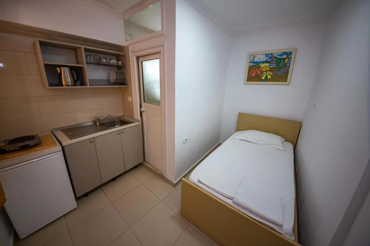 A studio with a single bed, a kitchenette with shelves and a door out to the courtyard