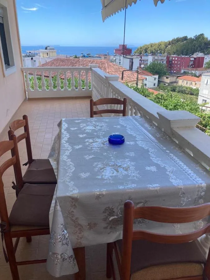 A terrace table laid with a lace cloth, chairs around it and the sea over the rooftops