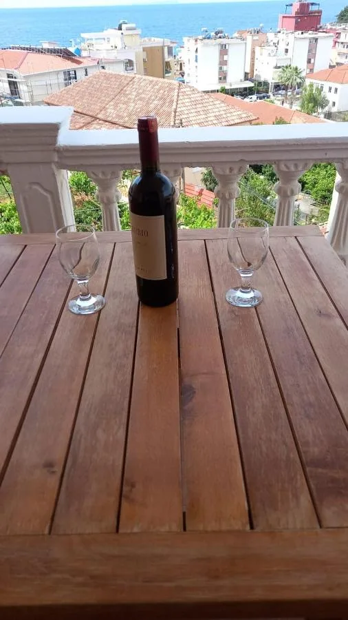A bottle of red wine and two glasses on a wooden terrace table