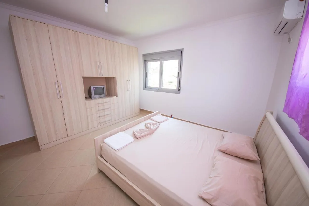 A double bed beside a built-in wardrobe with a television shelf