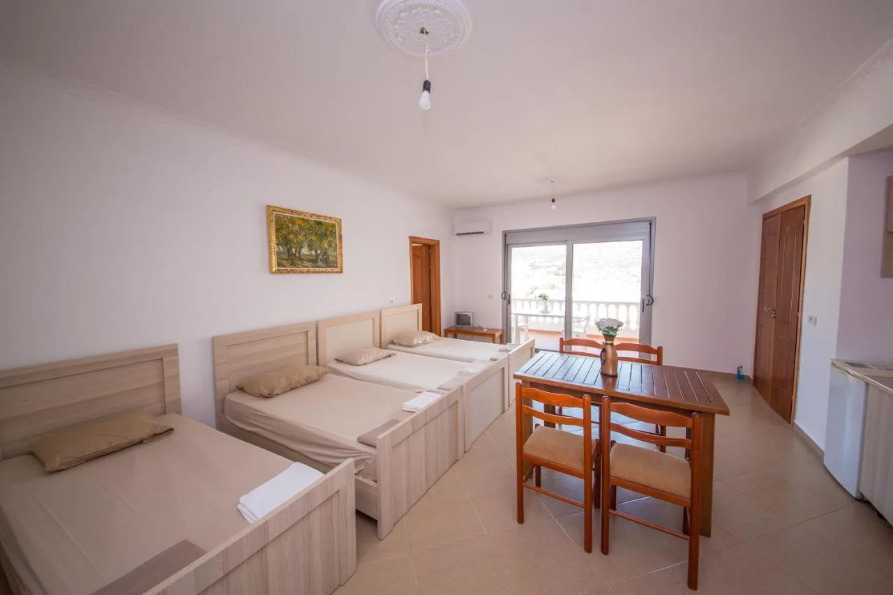 Beds along the living-room wall and a dining table by the door to the balcony