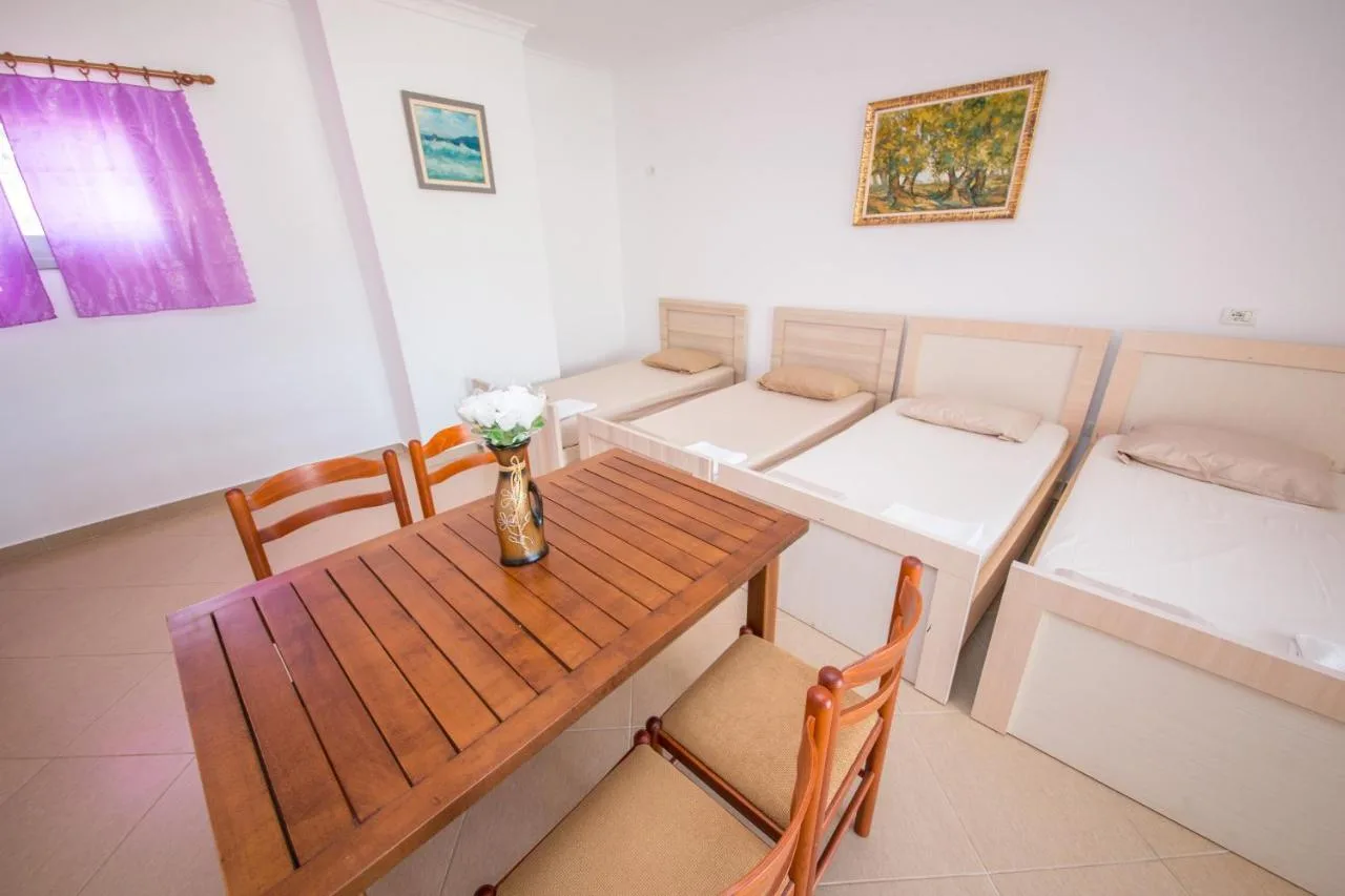 A wooden dining table with chairs in front of a row of sofa beds