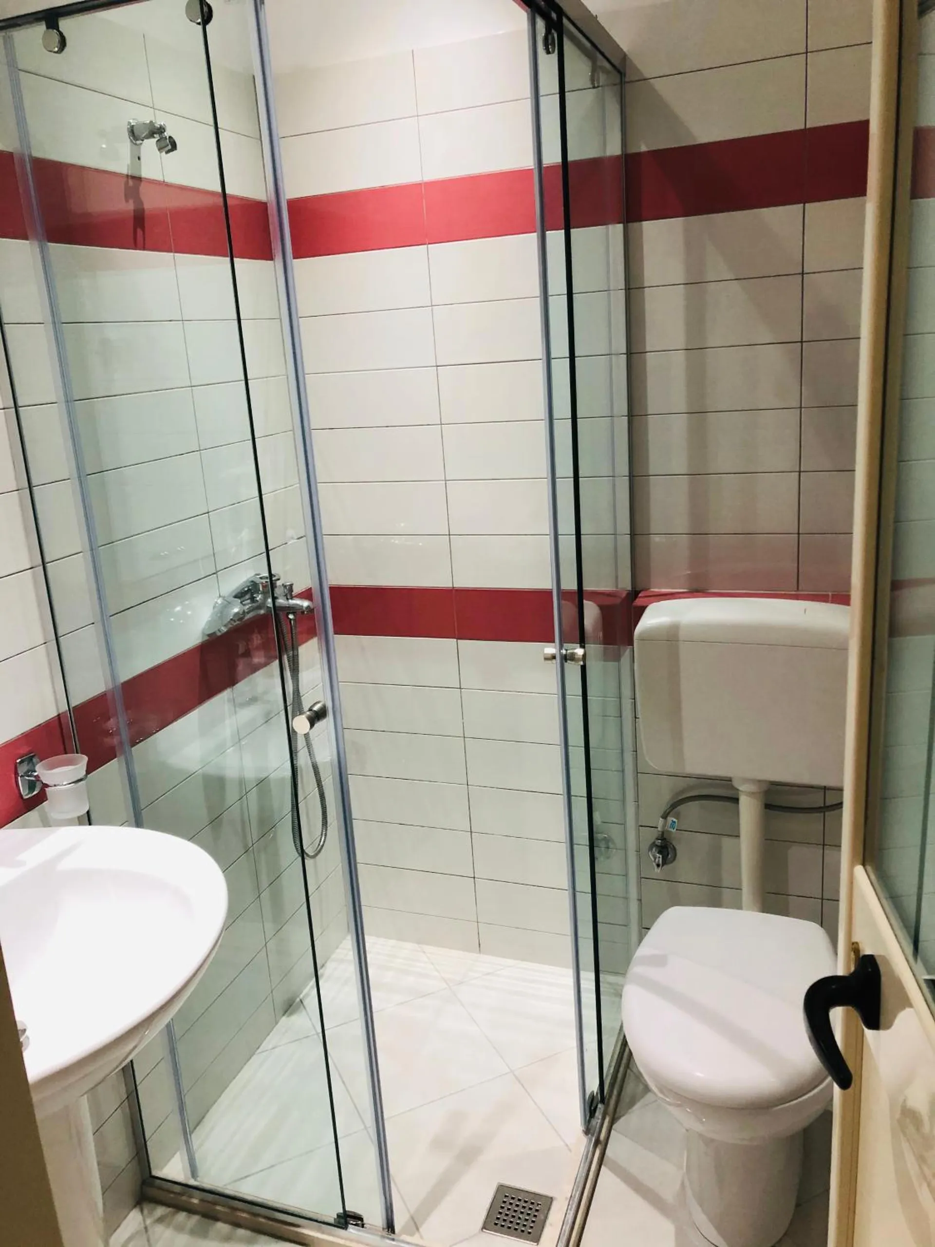 A tiled shower room with a glass screen and a basin