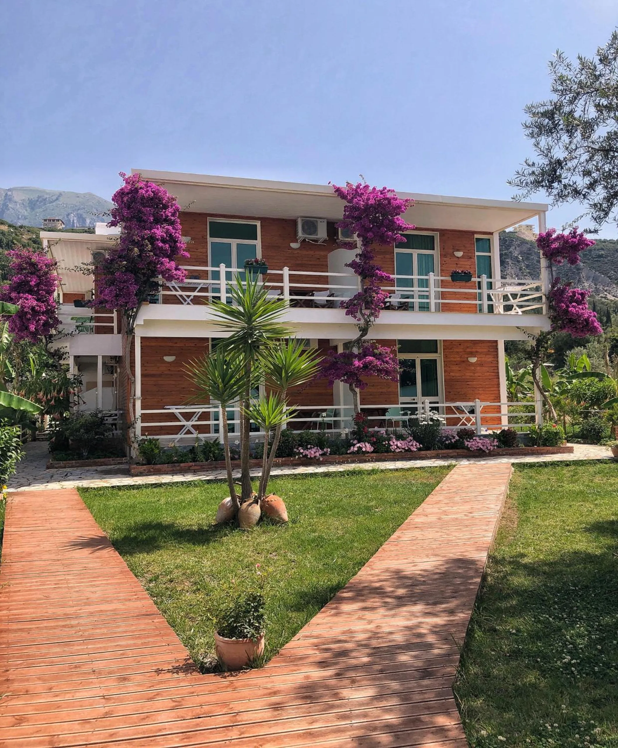 Brick paths across the lawn to the house, the bougainvillea in flower on the balcony posts