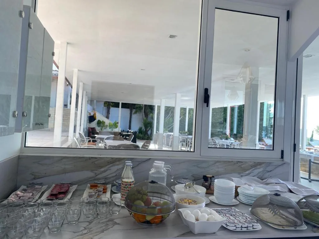 The breakfast buffet on a marble counter: cold meats, fruit in a basket, eggs, glasses and jugs, with the terrace seen through the window above