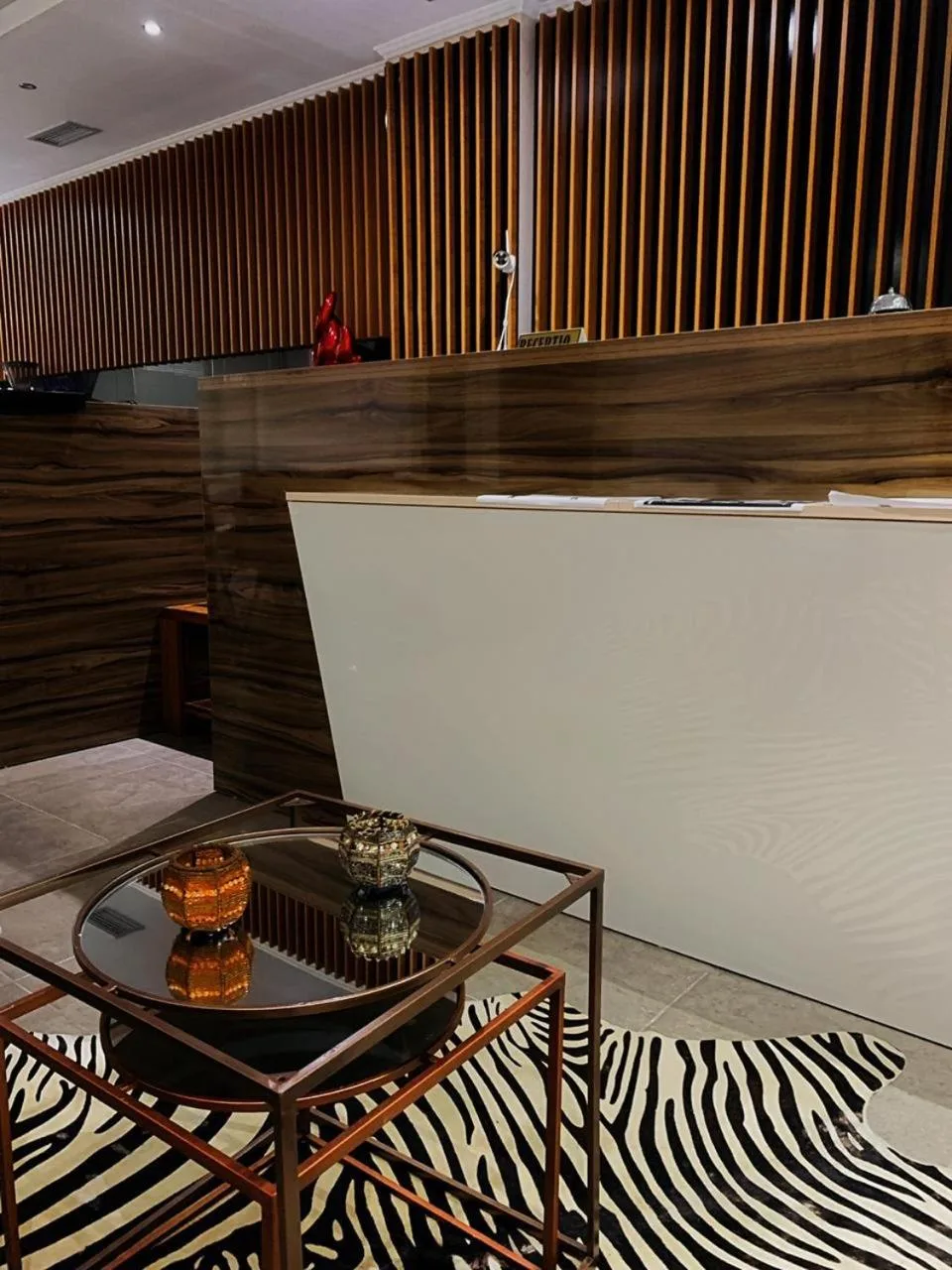 A glass and gold side table on a zebra-print rug in front of the reception desk