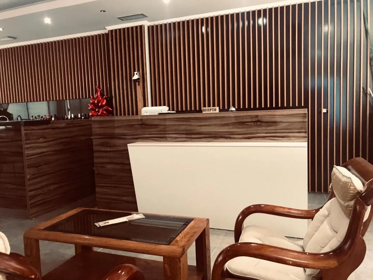 The reception desk in front of a wall of dark timber slats, with two armchairs and a glass table in the foreground