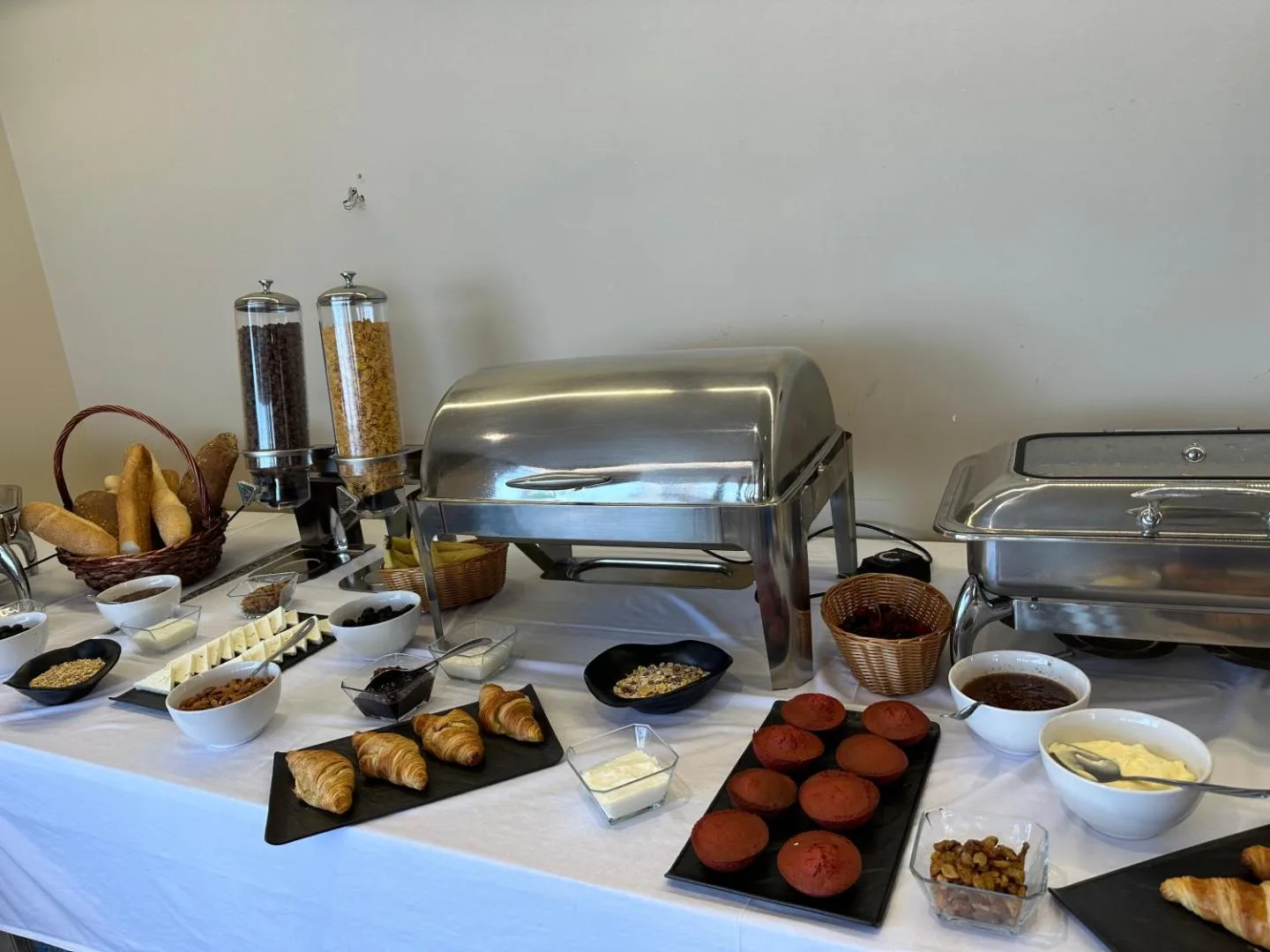 The breakfast buffet: bread, croissants, muffins, cereals, cheese and covered hot dishes