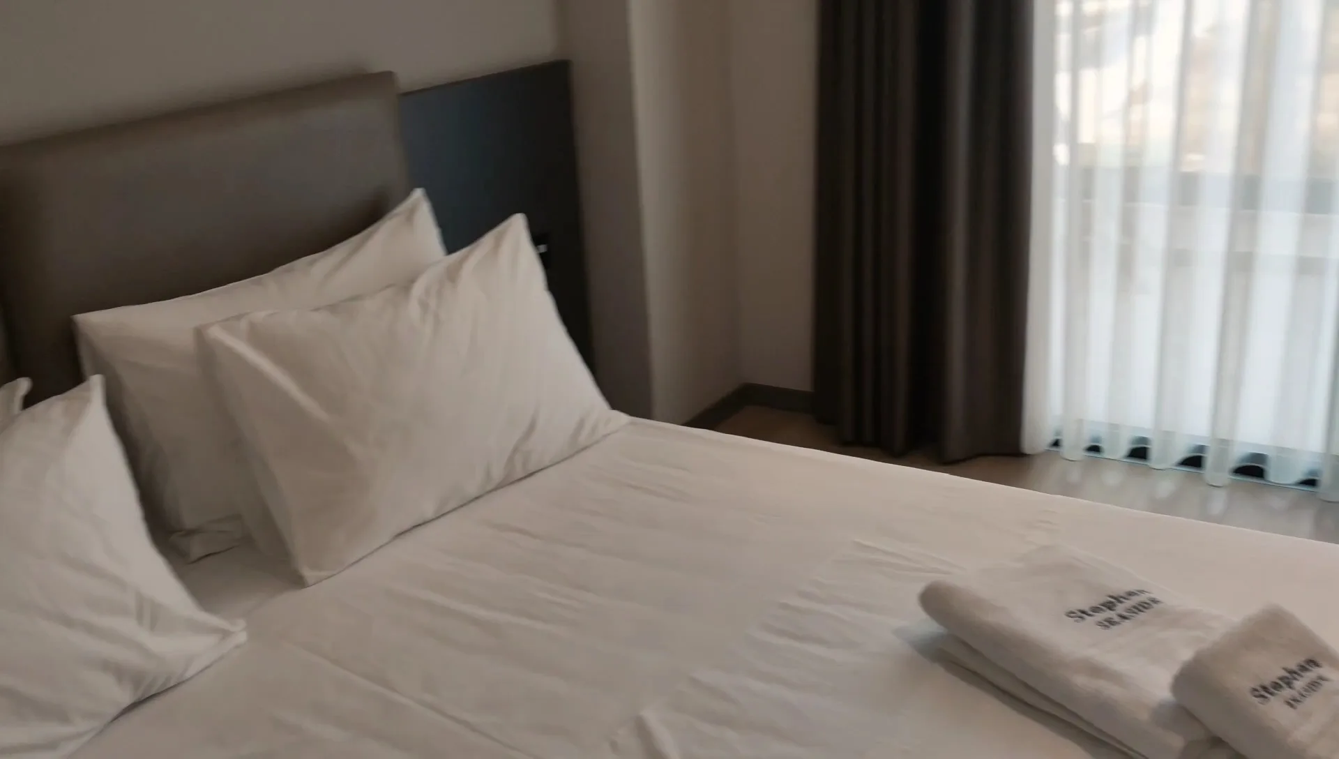 Folded towels embroidered Stephen Seaside on a made bed