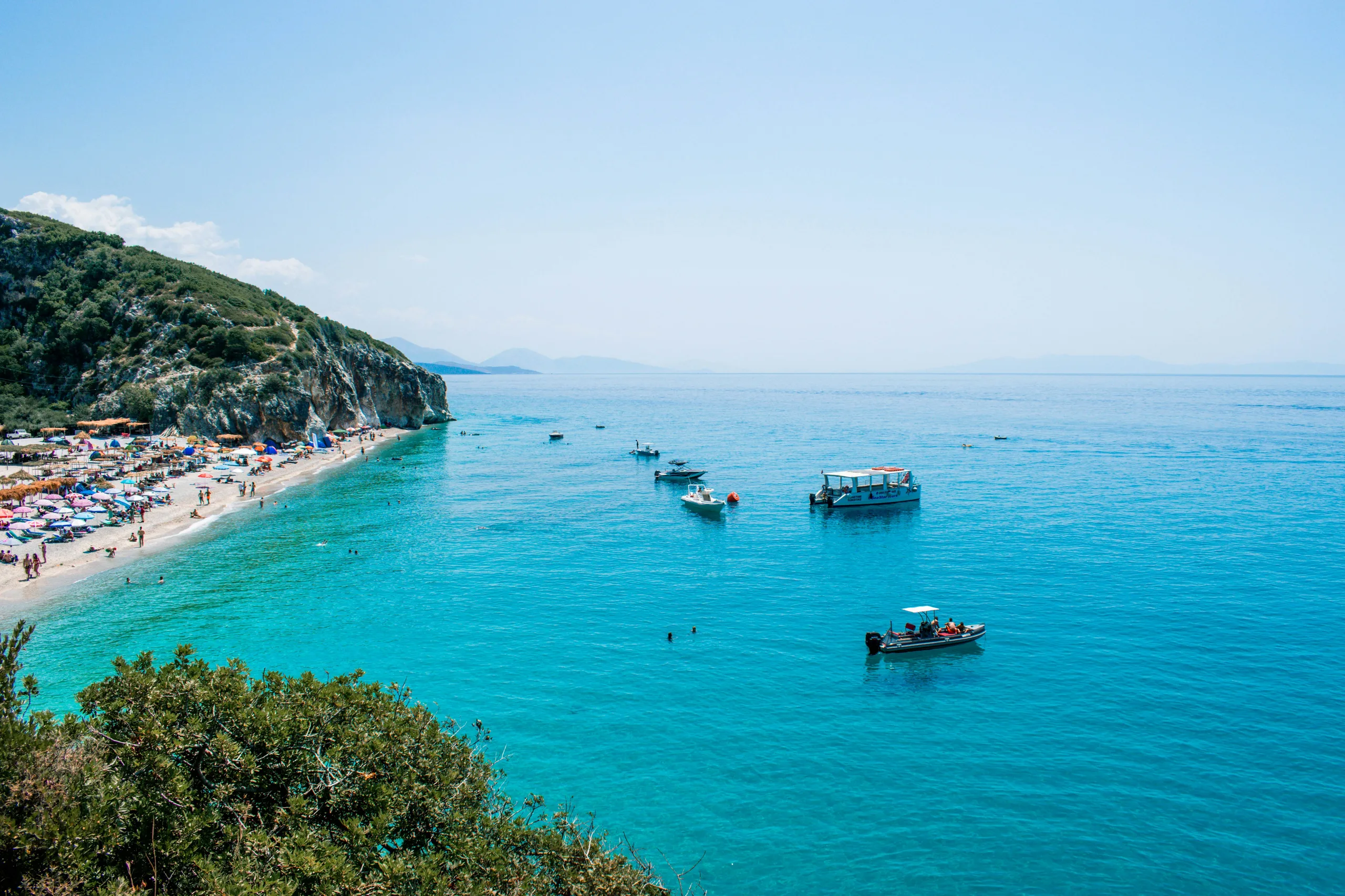 Gjipe Beach at the mouth of its canyon, with turquoise water and small boats at anchor