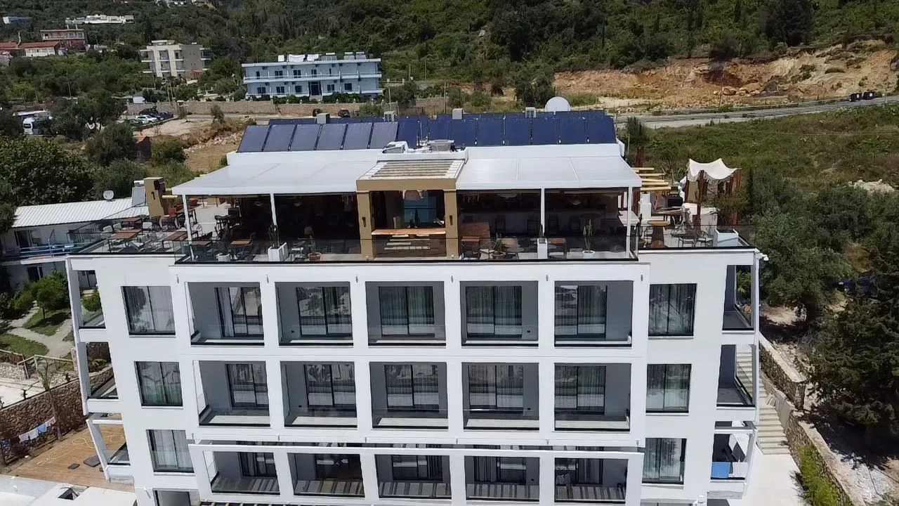 The roof terrace seen from a drone, with tables, a timber pavilion and solar panels above the top floor of rooms