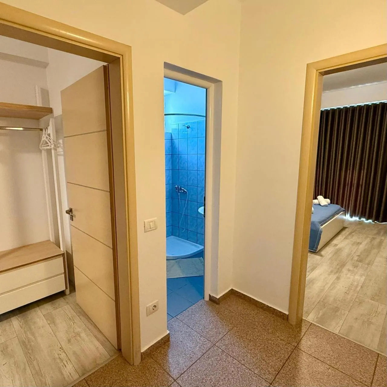 An oak hanging rail and drawers in the hall, the door open on a blue-tiled shower room