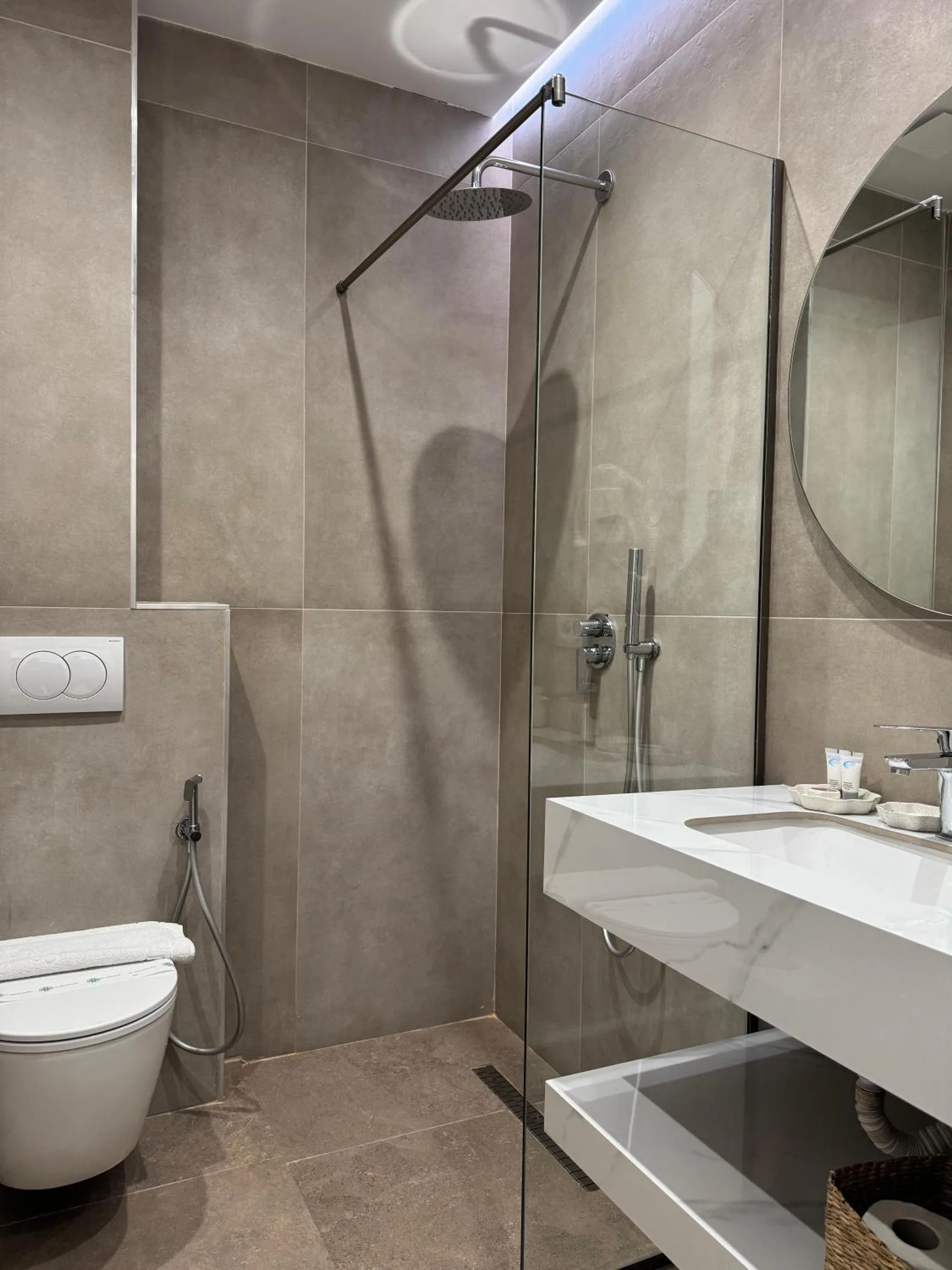 The Deluxe Room's shower room: a glass shower, a wall-hung toilet and a marble basin