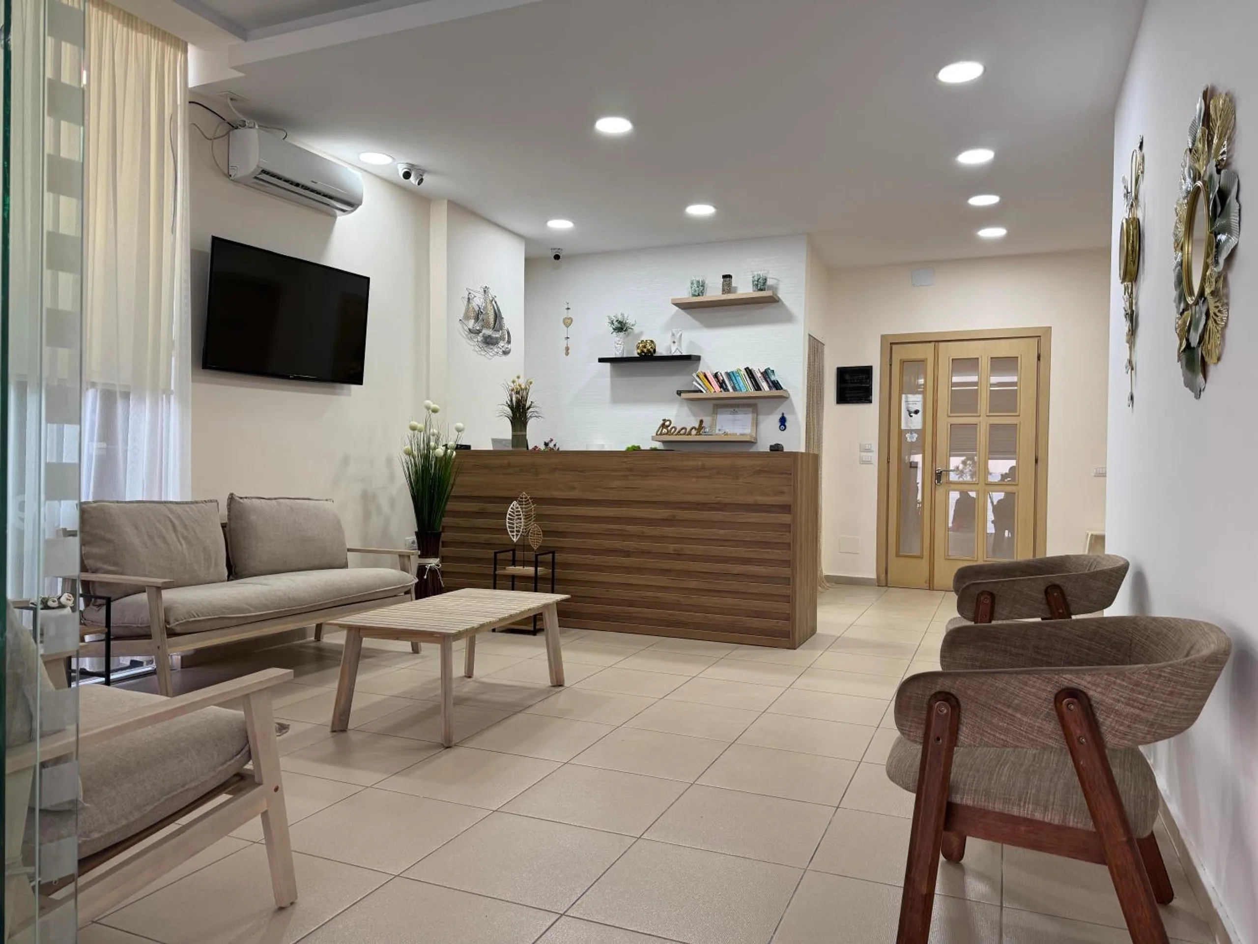 The ground-floor lounge: a sofa, armchairs and a low table on pale tile, with the timber reception desk behind