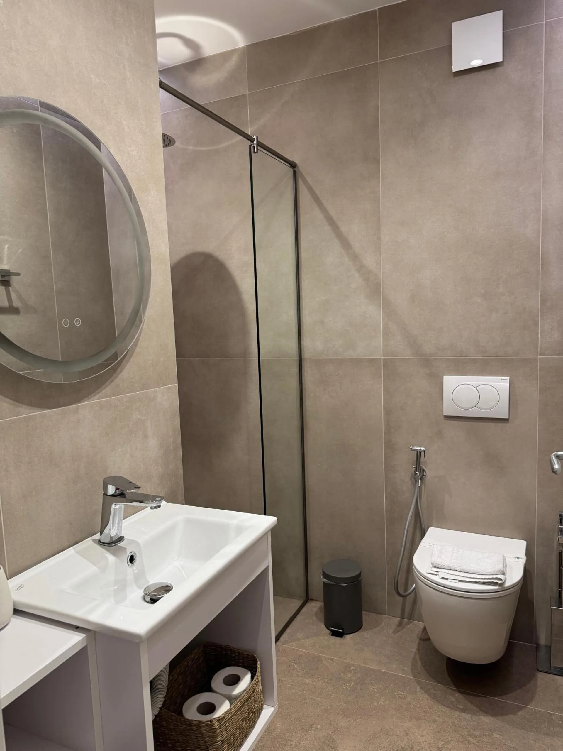 The mountain-view double's shower room: a round mirror, a white basin and a glass shower
