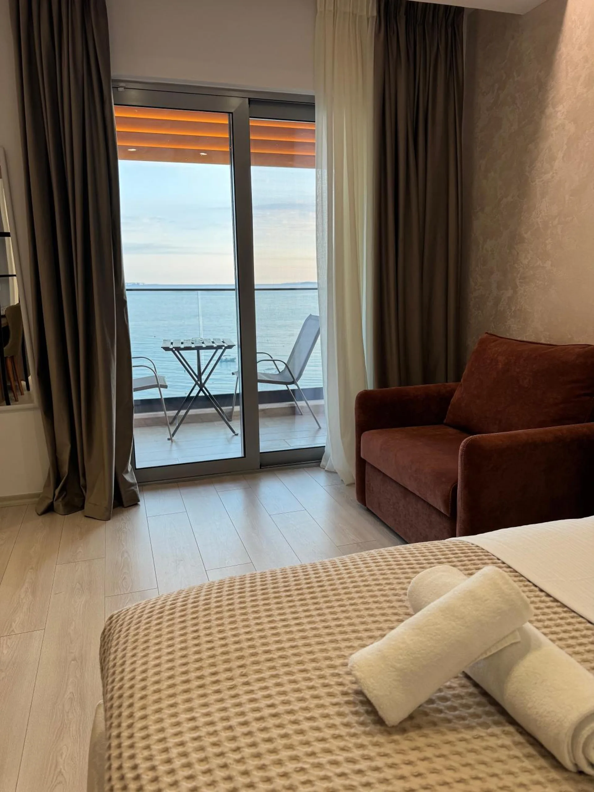 Inside a sea-view triple, a sofa beside the open balcony door and the sea through the glass