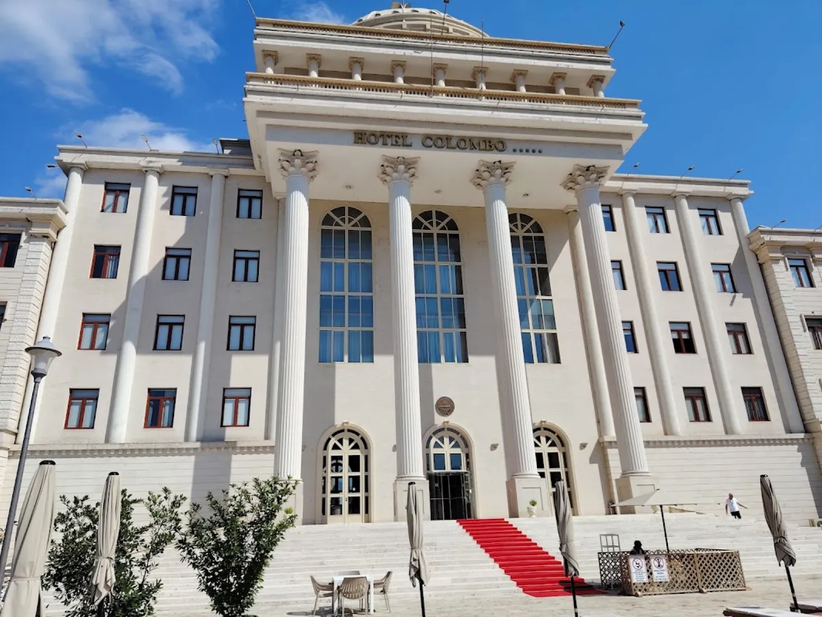 Hotel Colombo in Berat, a large cream building with a columned portico and a red carpet up the front steps