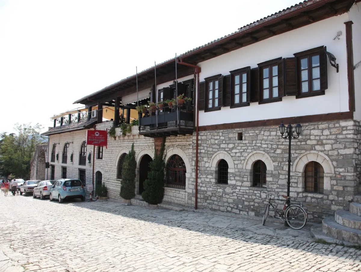 Hotel Mangalemi in Berat, a whitewashed Ottoman house with dark wooden windows above a stone ground floor on a cobbled lane