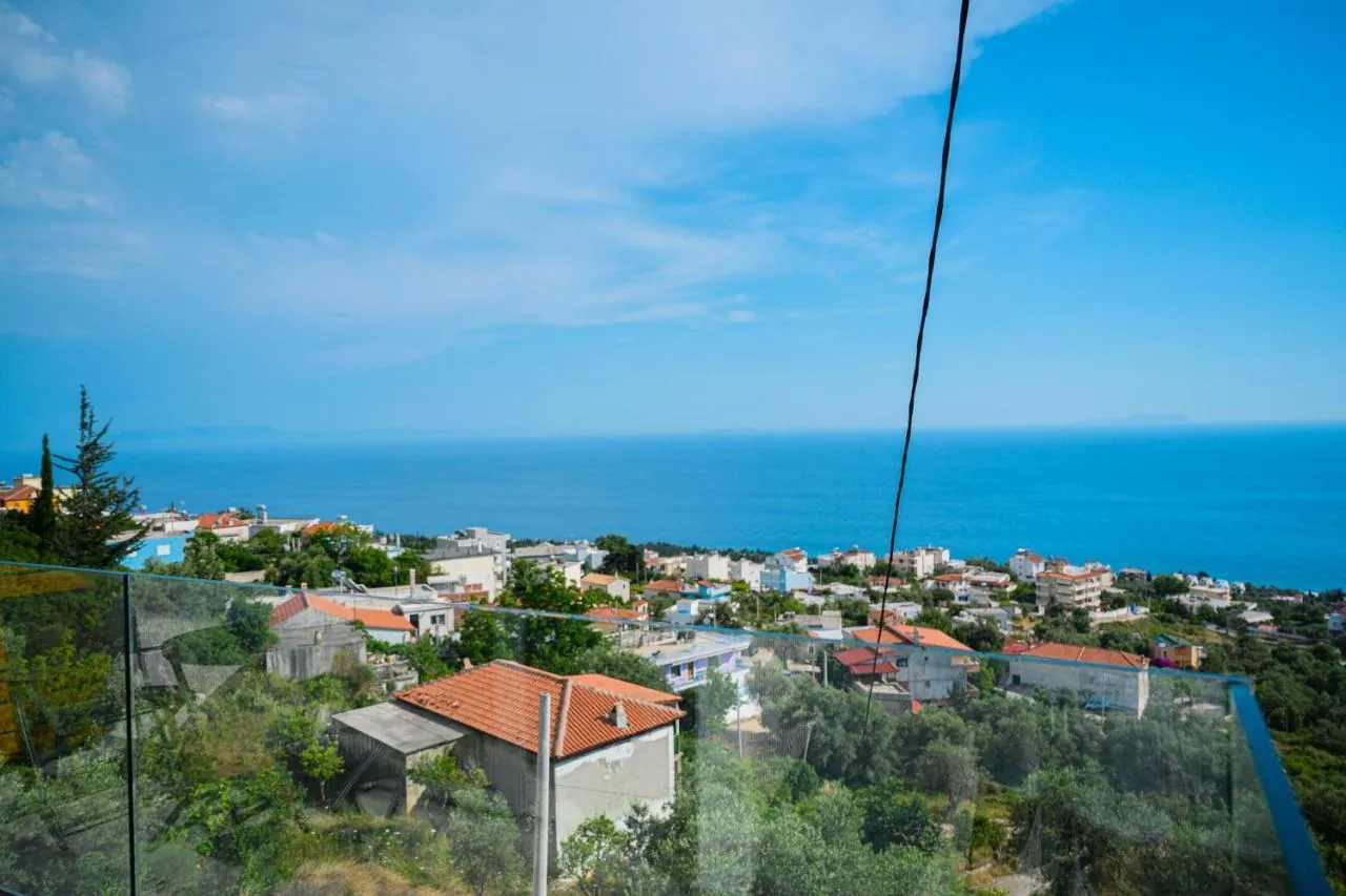 The view from Ionian Pearl over a glass balustrade: olive trees, red-tiled roofs of Drymades and the open sea to the horizon